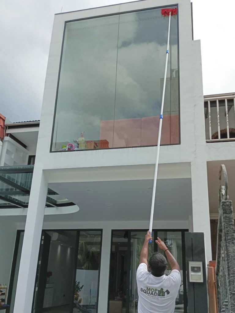 guy use extended squeegee to clean the window