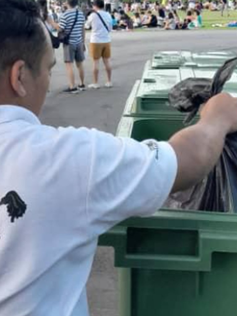 person throwing trash into green recycling bin